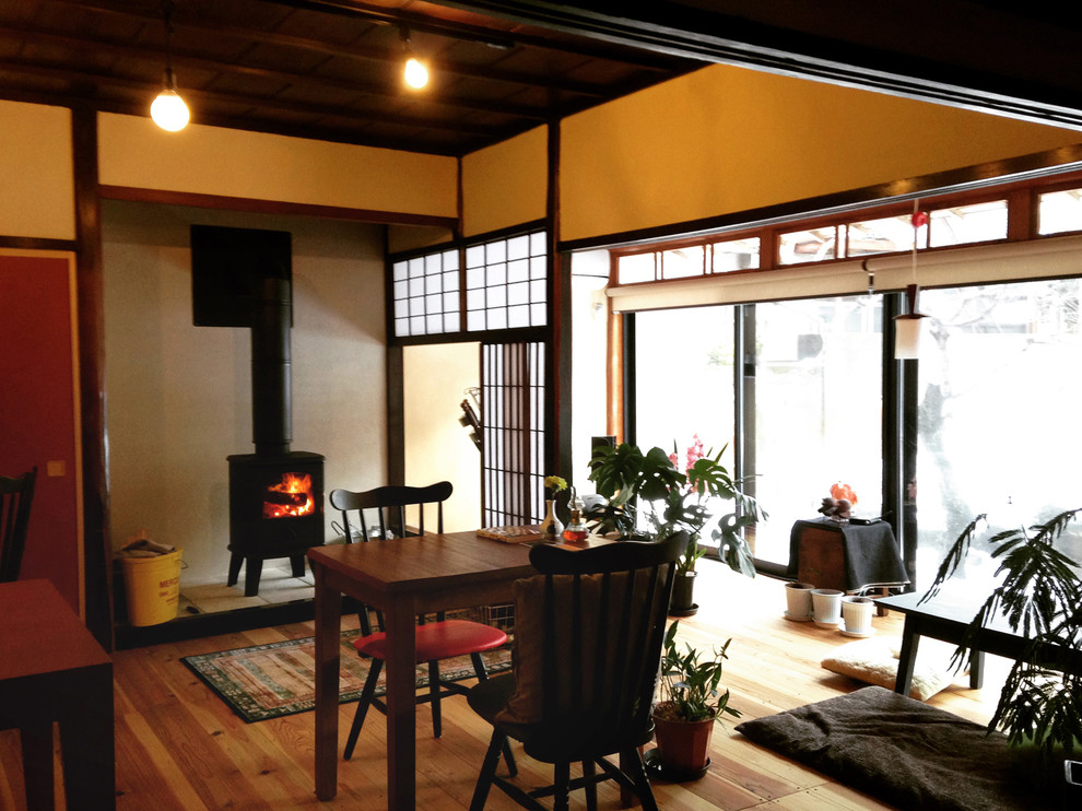 Design ideas for a small asian open concept living room in Other with beige walls, light hardwood floors, a wood stove, a plaster fireplace surround and beige floor.