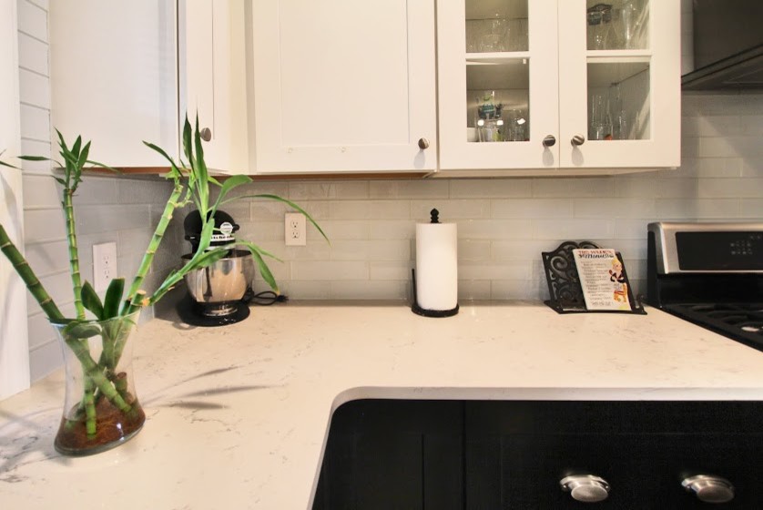 Inspiration for a mid-sized transitional l-shaped dark wood floor kitchen remodel in Philadelphia with a farmhouse sink, stainless steel appliances, shaker cabinets, quartzite countertops, white backsplash, subway tile backsplash and an island