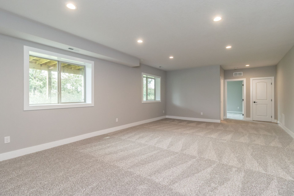 Inspiration for a large transitional look-out carpeted and gray floor basement remodel with gray walls