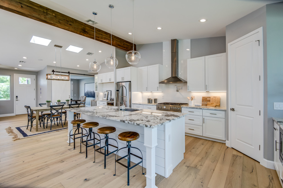 Inspiration for a large transitional galley light wood floor and beige floor open concept kitchen remodel in Phoenix with an undermount sink, shaker cabinets, white cabinets, white backsplash, subway tile backsplash, stainless steel appliances, an island and multicolored countertops