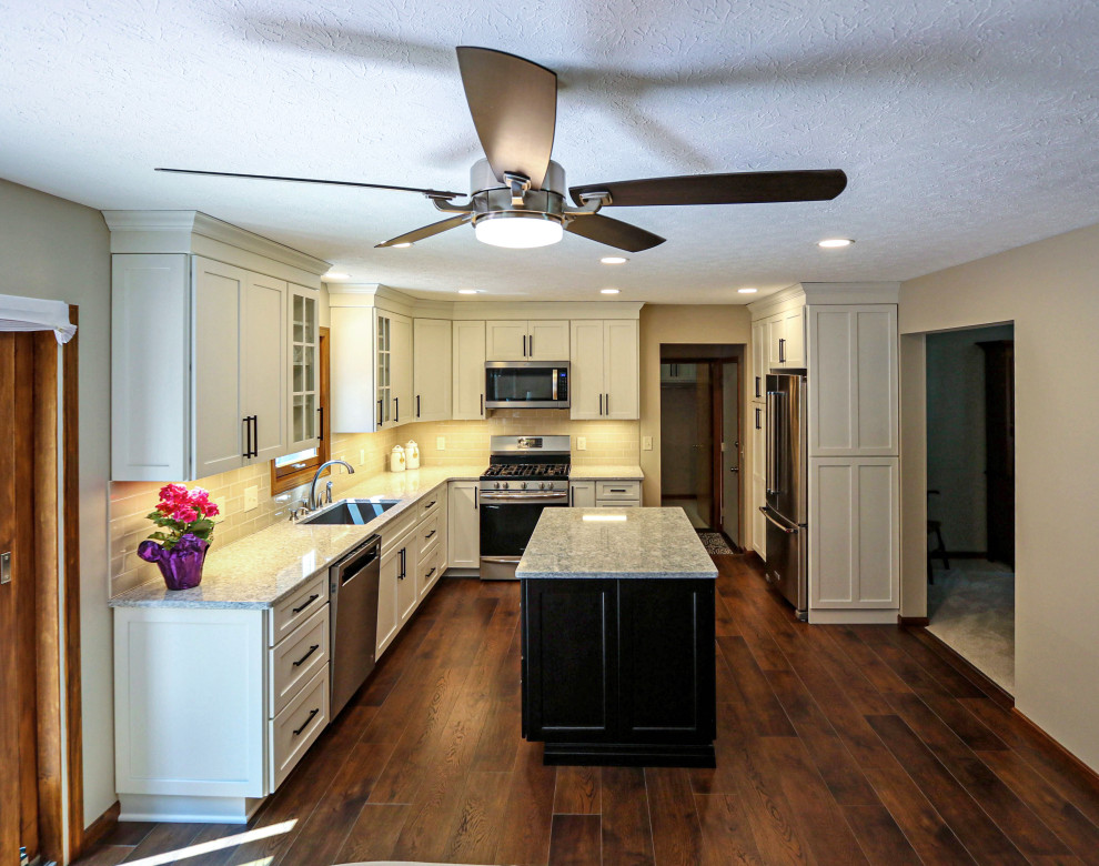Inredning av ett klassiskt mellanstort flerfärgad flerfärgat kök, med en undermonterad diskho, släta luckor, vita skåp, bänkskiva i kvarts, grått stänkskydd, stänkskydd i porslinskakel, rostfria vitvaror, vinylgolv, en köksö och brunt golv