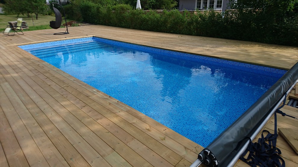Idée de décoration pour une piscine arrière de taille moyenne et sur mesure avec une terrasse en bois.