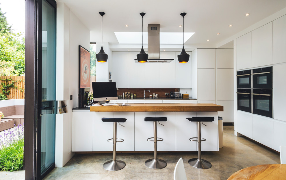 Design ideas for a mid-sized contemporary u-shaped eat-in kitchen in London with flat-panel cabinets, white cabinets, wood benchtops, brown splashback, timber splashback, black appliances, a peninsula and beige benchtop.