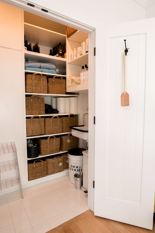 Inspiration for a small beach style galley utility room in Other with flat-panel cabinets, white cabinets, white walls, ceramic floors, a stacked washer and dryer and a single-bowl sink.