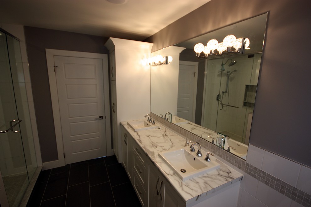 Inspiration for a mid-sized contemporary master bathroom in Toronto with a drop-in sink, recessed-panel cabinets, white cabinets, laminate benchtops, a drop-in tub, a shower/bathtub combo, a two-piece toilet, gray tile, ceramic tile, grey walls and ceramic floors.