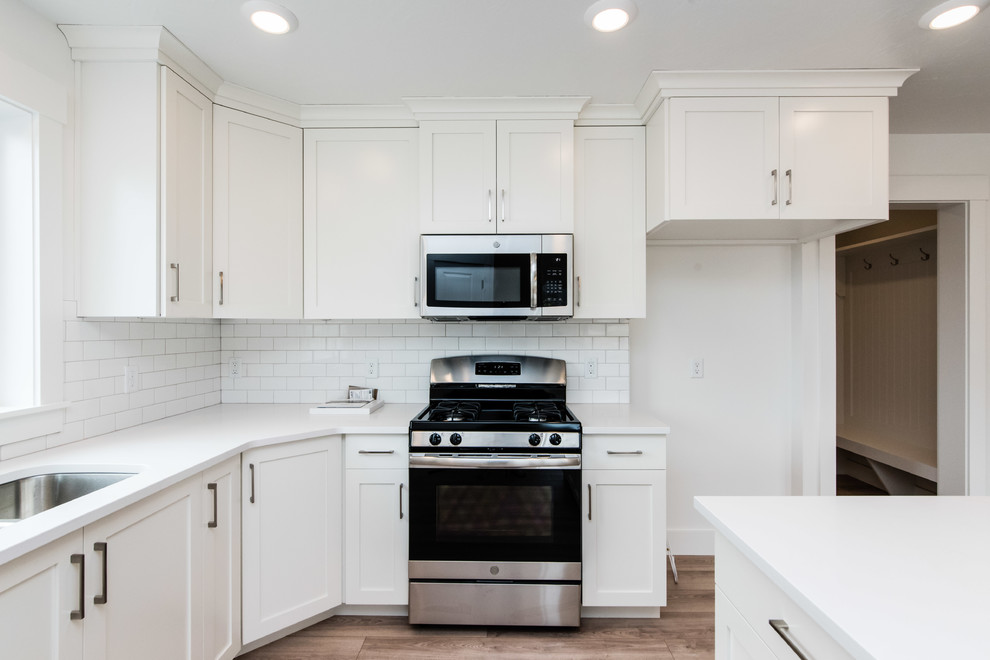 Design ideas for an arts and crafts open plan kitchen in Salt Lake City with white splashback, subway tile splashback, stainless steel appliances, with island and white benchtop.