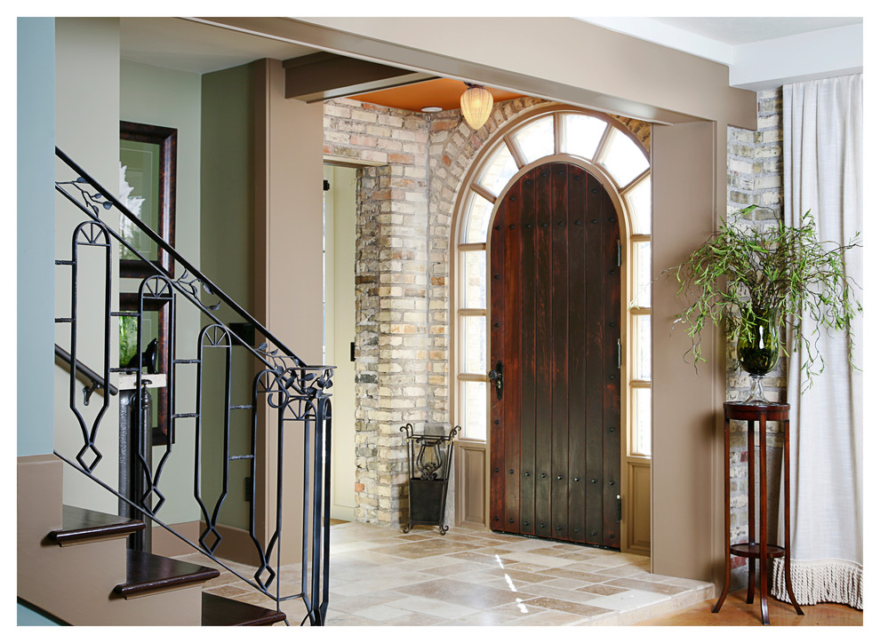 Photo of a large transitional foyer in Grand Rapids with multi-coloured walls, limestone floors, a single front door and a dark wood front door.