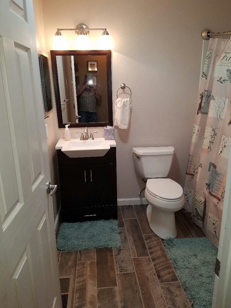 Small transitional porcelain tile and brown floor alcove bathtub photo with shaker cabinets, dark wood cabinets, a two-piece toilet, white walls and an integrated sink