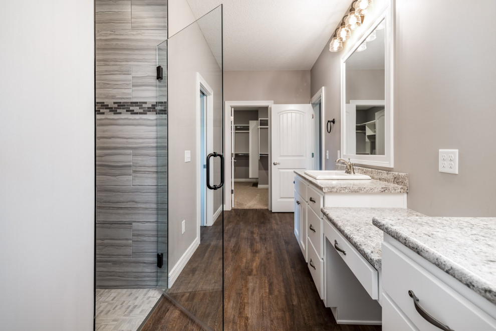 Transitional master vinyl floor and brown floor walk-in shower photo with shaker cabinets, white cabinets, gray walls, a drop-in sink, laminate countertops and a hinged shower door