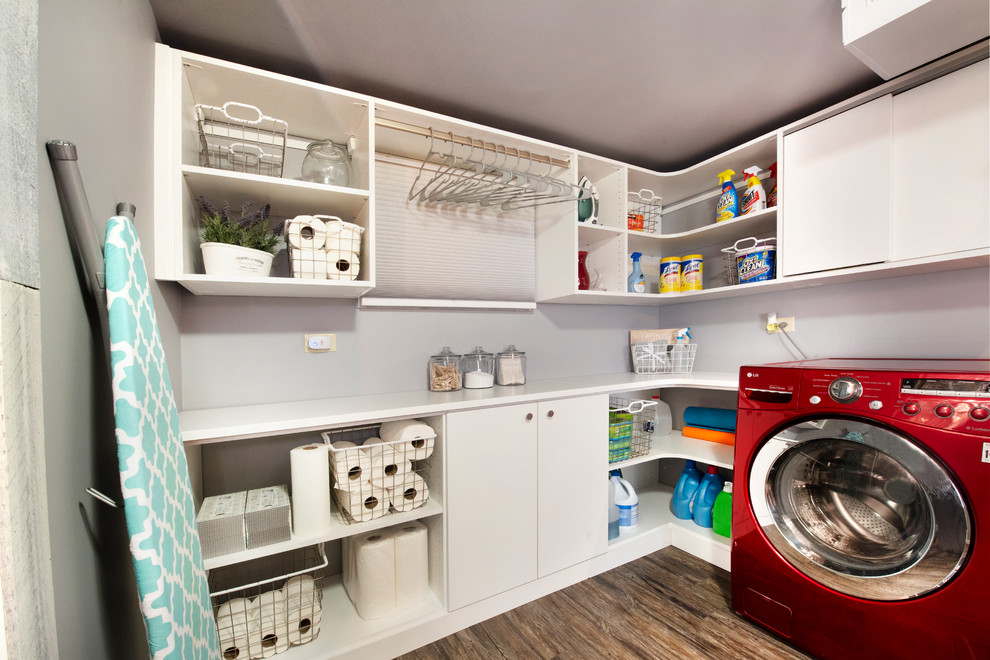 Design ideas for a mid-sized modern dedicated laundry room in Chicago with flat-panel cabinets, white cabinets, laminate benchtops, grey walls, vinyl floors, an integrated washer and dryer, brown floor and white benchtop.