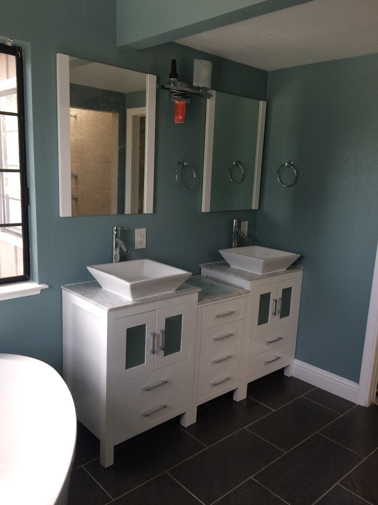 This is an example of a mid-sized eclectic master bathroom in San Francisco with flat-panel cabinets, white cabinets, a claw-foot tub, an alcove shower, a one-piece toilet, white tile, matchstick tile, blue walls, a vessel sink, marble benchtops and ceramic floors.