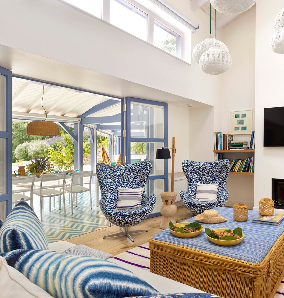 Photo of a mid-sized beach style enclosed family room in Madrid with white walls, light hardwood floors and a wall-mounted tv.