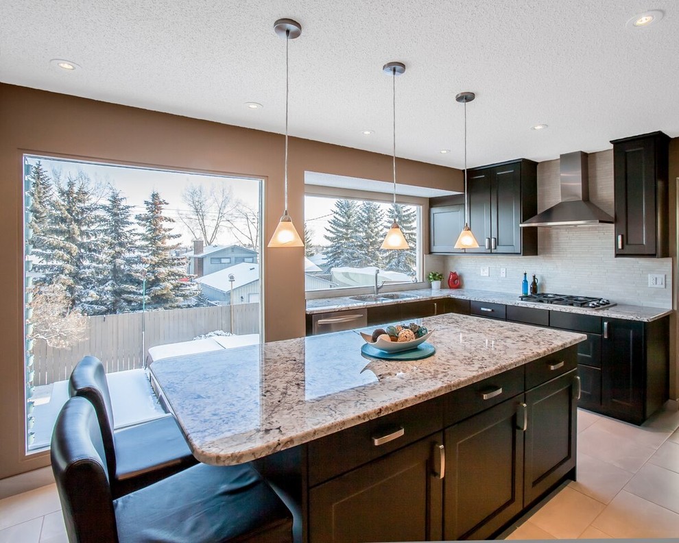 Enclosed kitchen - mid-sized transitional u-shaped ceramic tile and beige floor enclosed kitchen idea in Calgary with a double-bowl sink, shaker cabinets, dark wood cabinets, granite countertops, beige backsplash, matchstick tile backsplash, stainless steel appliances and an island