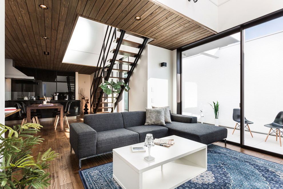 This is an example of an asian open concept living room in Nagoya with white walls, dark hardwood floors and brown floor.