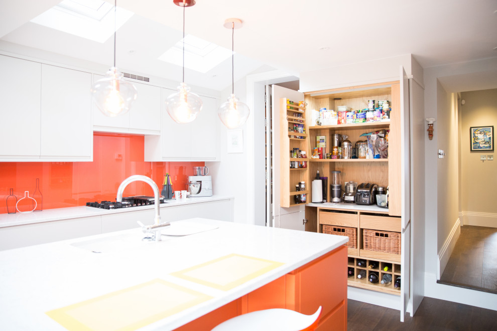 Inspiration for a mid-sized modern u-shaped open plan kitchen in London with a single-bowl sink, flat-panel cabinets, orange cabinets, solid surface benchtops, orange splashback, glass tile splashback, dark hardwood floors, with island, brown floor and white benchtop.