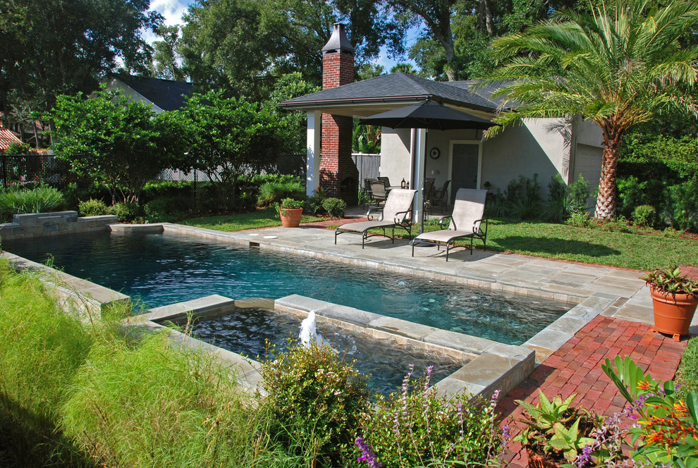 This is an example of a mid-sized contemporary rectangular pool in Orlando with natural stone pavers.