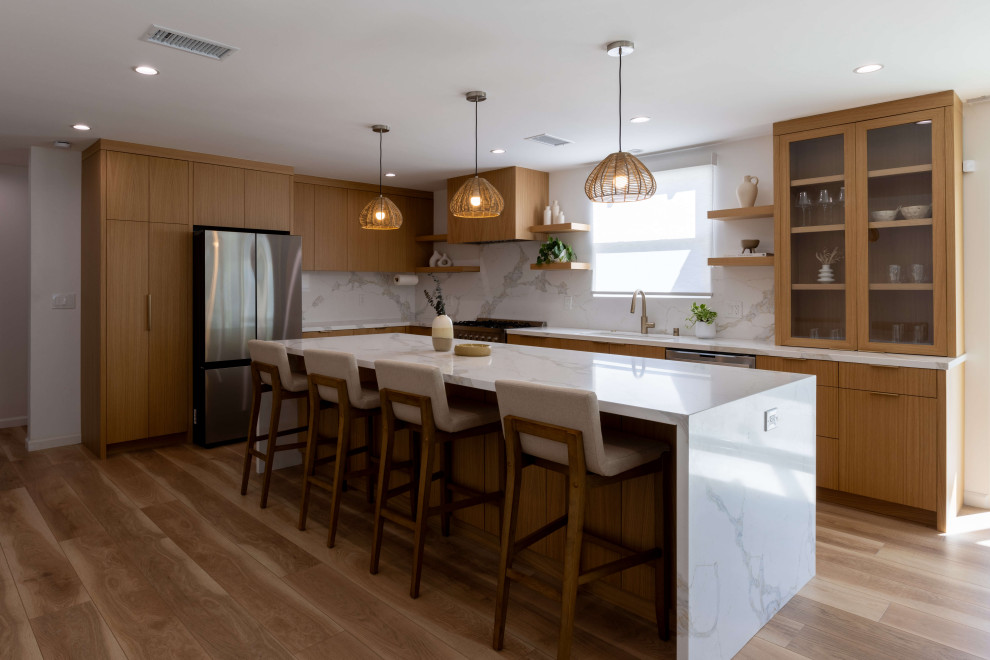 Exempel på ett mellanstort modernt vit vitt kök och matrum, med skåp i mellenmörkt trä, bänkskiva i kvarts, vitt stänkskydd, rostfria vitvaror, laminatgolv, en köksö och brunt golv