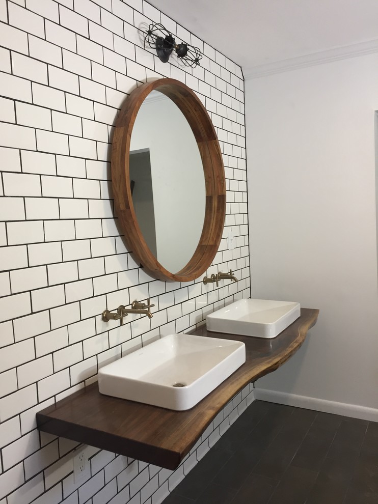 This is an example of a mid-sized contemporary master bathroom in Baltimore with a curbless shower, a wall-mount toilet, white tile, subway tile, a vessel sink, wood benchtops, a hinged shower door, furniture-like cabinets, dark wood cabinets, white walls, dark hardwood floors, brown floor and brown benchtops.