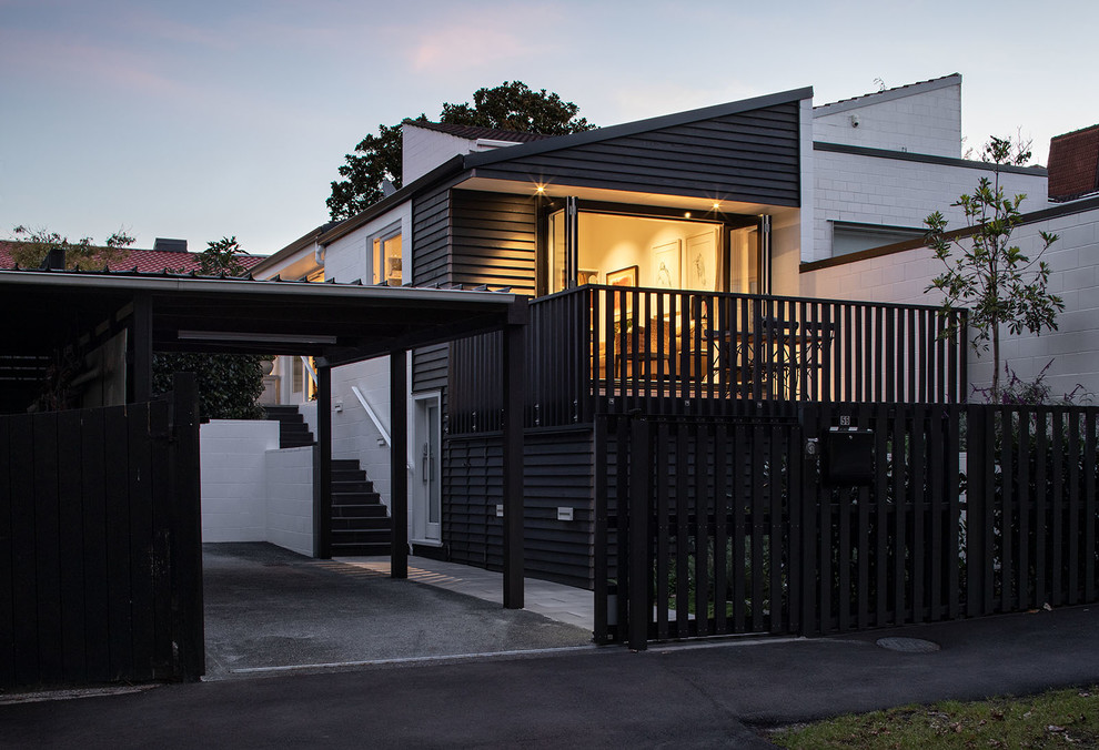 Photo of a small contemporary one-storey black townhouse exterior in Auckland with wood siding, a gable roof and a mixed roof.
