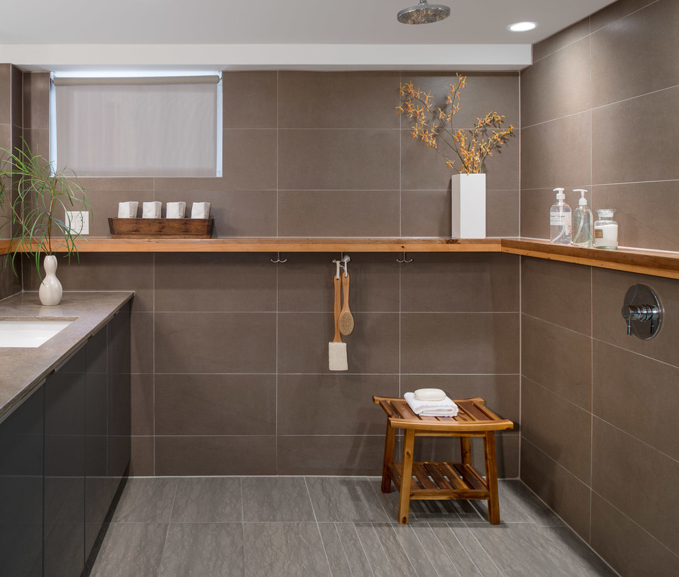 Photo of a small eclectic bathroom in Toronto with an undermount sink, flat-panel cabinets, grey cabinets, limestone benchtops, a curbless shower, gray tile, porcelain tile, limestone floors, a one-piece toilet and grey walls.