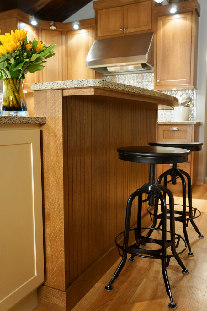 Inspiration for a rustic light wood floor kitchen remodel with an undermount sink, shaker cabinets, yellow cabinets, solid surface countertops, metallic backsplash and stainless steel appliances