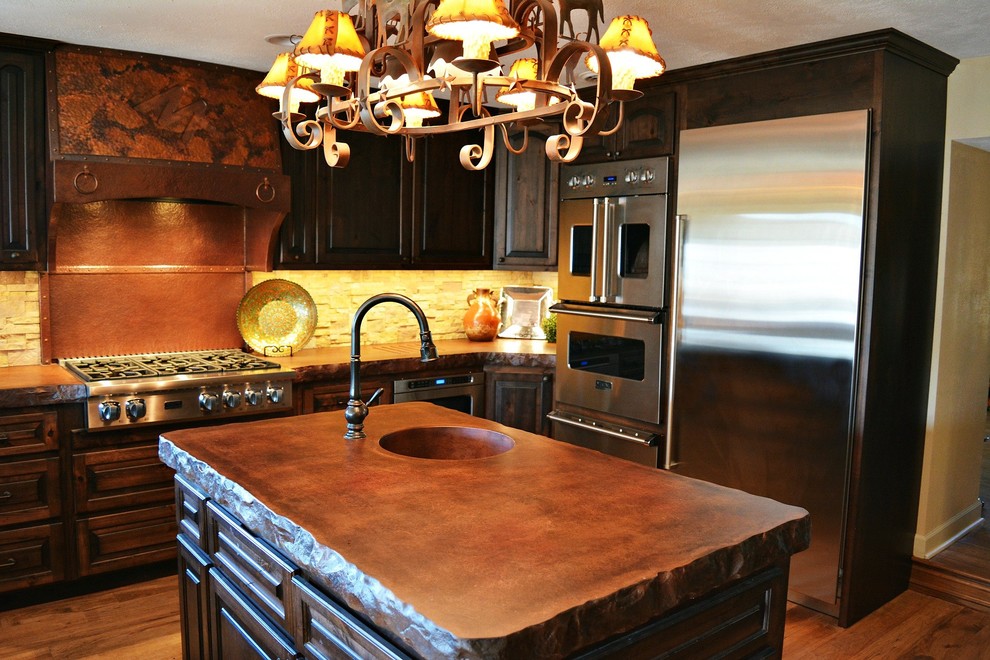 Inspiration for a large country u-shaped eat-in kitchen in Kansas City with a farmhouse sink, shaker cabinets, dark wood cabinets, concrete benchtops, beige splashback, stone tile splashback, stainless steel appliances, medium hardwood floors, multiple islands, brown floor and brown benchtop.