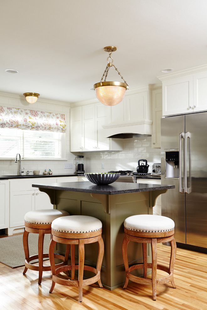 Design ideas for a traditional l-shaped kitchen in Minneapolis with shaker cabinets, white cabinets, granite benchtops, white splashback, subway tile splashback, stainless steel appliances, medium hardwood floors and with island.