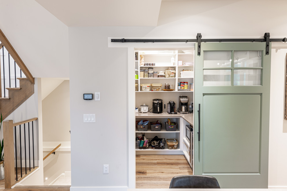Inspiration for a mid-sized transitional l-shaped laminate floor and brown floor eat-in kitchen remodel in Toronto with an undermount sink, recessed-panel cabinets, white cabinets, quartz countertops, stainless steel appliances, an island and white countertops