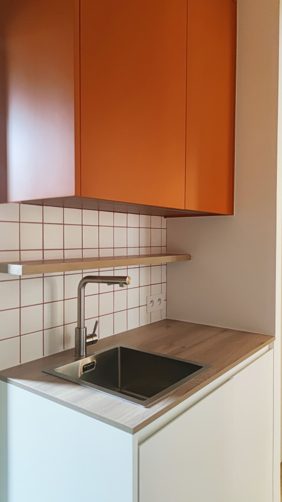 Idéer för ett mellanstort 50 tals brun linjärt kök med öppen planlösning, med en enkel diskho, luckor med profilerade fronter, orange skåp, laminatbänkskiva, vitt stänkskydd, stänkskydd i keramik, vita vitvaror, ljust trägolv och flera köksöar