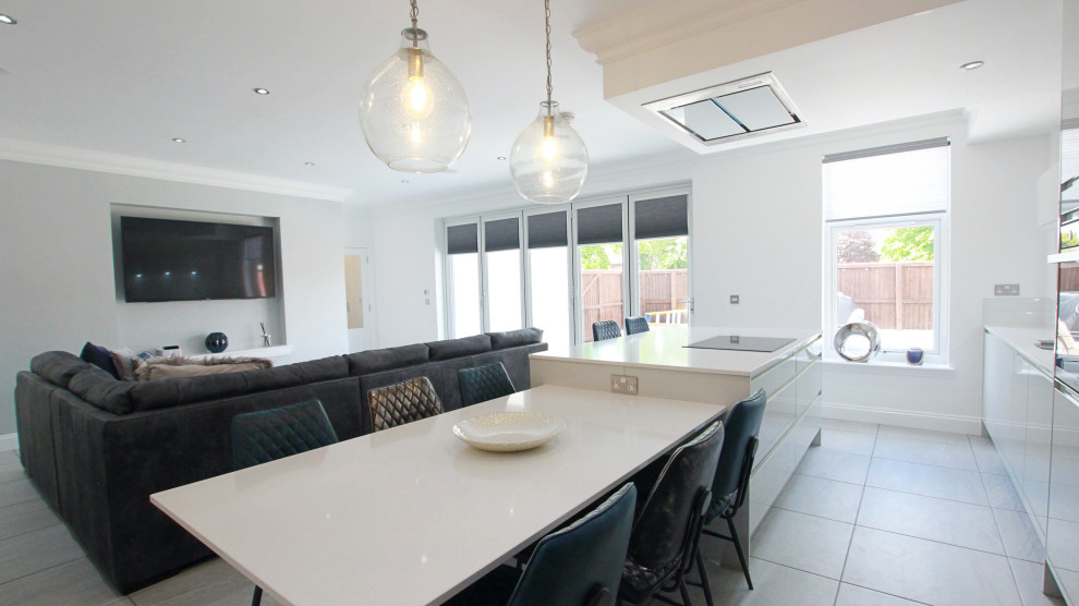 Large contemporary galley open plan kitchen in Glasgow with an integrated sink, flat-panel cabinets, grey cabinets, quartzite benchtops, white splashback, granite splashback, black appliances, porcelain floors, with island, grey floor, white benchtop and recessed.