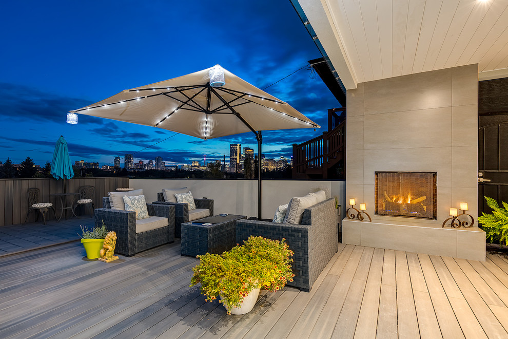 Design ideas for a transitional backyard deck in Calgary with a fire feature and a roof extension.