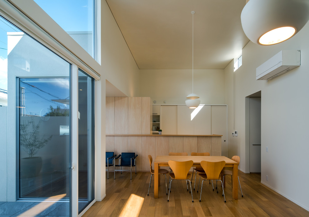Photo of an open plan dining in Osaka with white walls, plywood floors and brown floor.