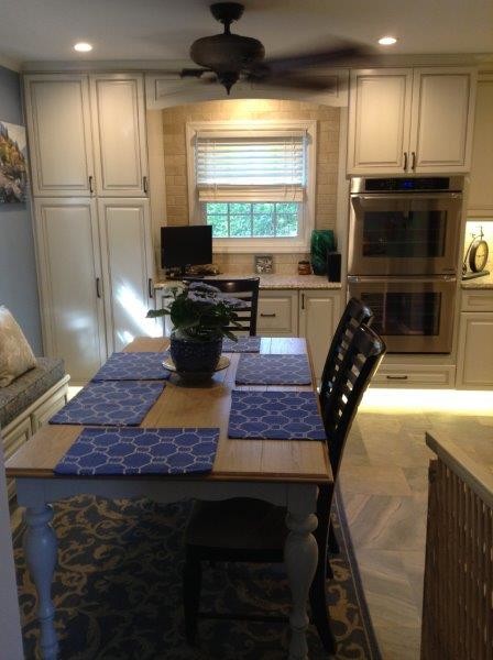 This is an example of an expansive mediterranean galley eat-in kitchen in Baltimore with an undermount sink, raised-panel cabinets, beige cabinets, wood benchtops, beige splashback, stone tile splashback, stainless steel appliances, porcelain floors and with island.