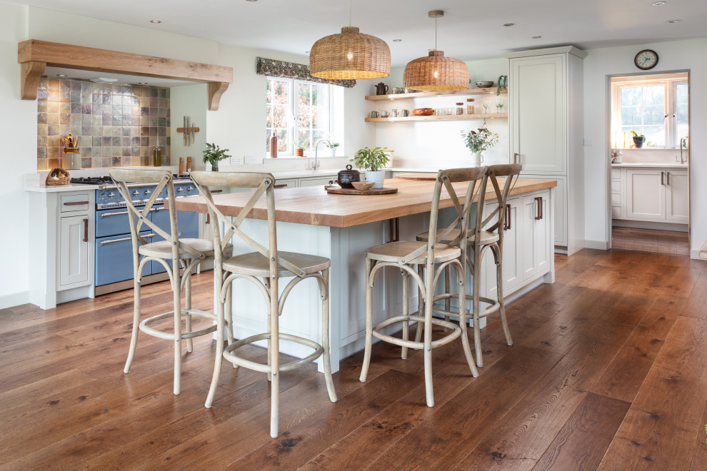 Transitional l-shaped kitchen in Cornwall with an undermount sink, shaker cabinets, white cabinets, wood benchtops, multi-coloured splashback, coloured appliances, medium hardwood floors, with island, brown floor and brown benchtop.