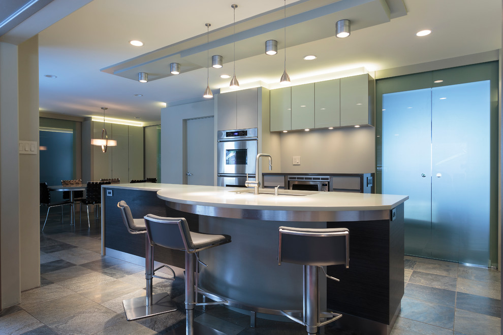 Inspiration for a mid-sized contemporary l-shaped eat-in kitchen in Other with an undermount sink, glass-front cabinets, dark wood cabinets, quartzite benchtops, grey splashback, glass sheet splashback, stainless steel appliances, slate floors and with island.