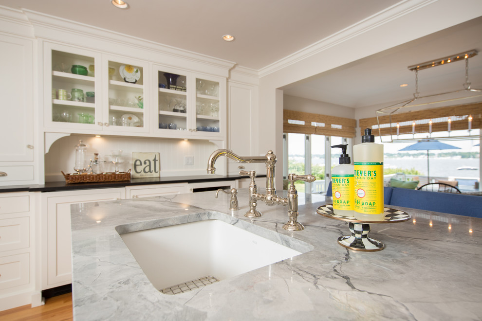 Transitional medium tone wood floor home design photo in Boston with a farmhouse sink, recessed-panel cabinets, white cabinets, granite countertops, white backsplash, subway tile backsplash, stainless steel appliances and two islands