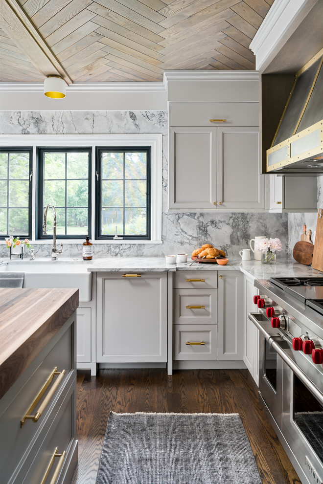 Mid-sized transitional medium tone wood floor and brown floor enclosed kitchen photo in Chicago with a farmhouse sink, recessed-panel cabinets, gray cabinets, quartzite countertops, gray backsplash, stone slab backsplash, paneled appliances, an island and gray countertops