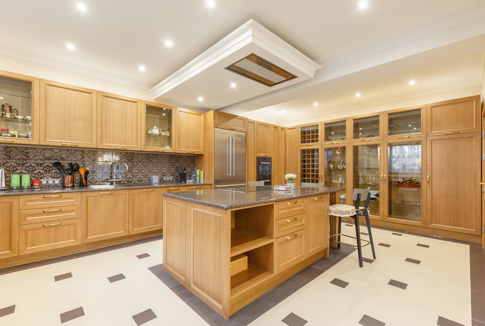Large traditional u-shaped eat-in kitchen in Other with an undermount sink, glass-front cabinets, brown cabinets, granite benchtops, black splashback, mirror splashback, black appliances, porcelain floors, with island, beige floor and grey benchtop.