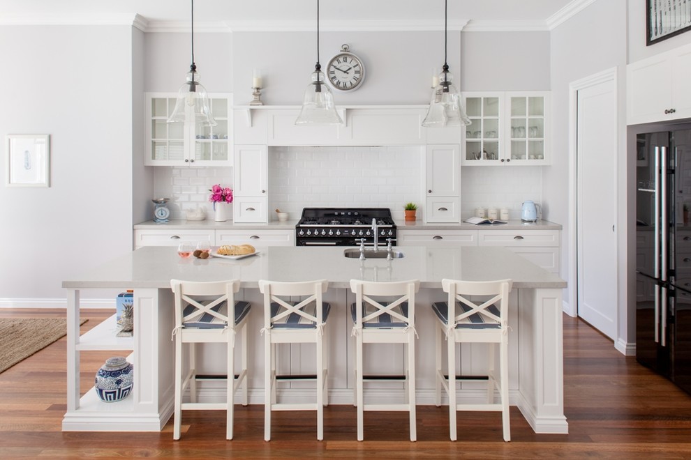 Inspiration for a traditional kitchen in Brisbane with an undermount sink, glass-front cabinets, white cabinets, black appliances, dark hardwood floors and with island.