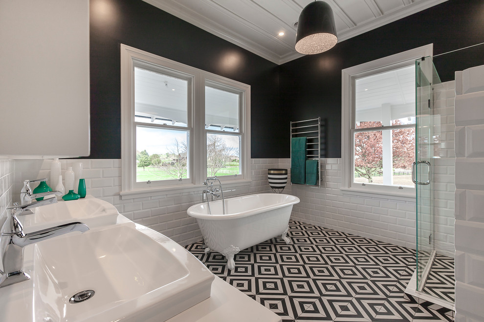 Large transitional master bathroom in Hamilton with recessed-panel cabinets, white cabinets, a claw-foot tub, a corner shower, a wall-mount toilet, white tile, subway tile, black walls, porcelain floors, a drop-in sink and solid surface benchtops.