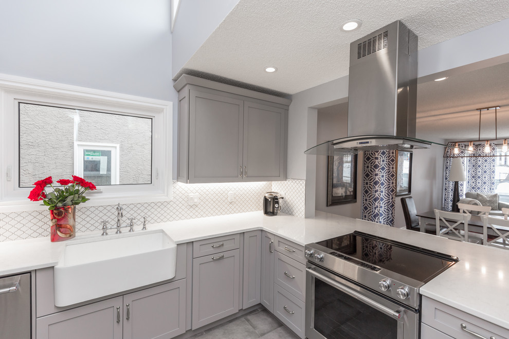 Inspiration for a transitional gray floor eat-in kitchen remodel in Calgary with a farmhouse sink, shaker cabinets, gray cabinets, quartz countertops, white backsplash and stainless steel appliances