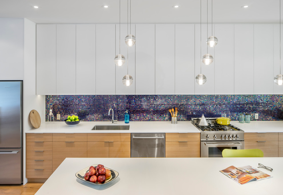 Small contemporary single-wall open plan kitchen in Toronto with an undermount sink, flat-panel cabinets, medium wood cabinets, quartz benchtops, blue splashback, glass tile splashback, stainless steel appliances, medium hardwood floors and with island.