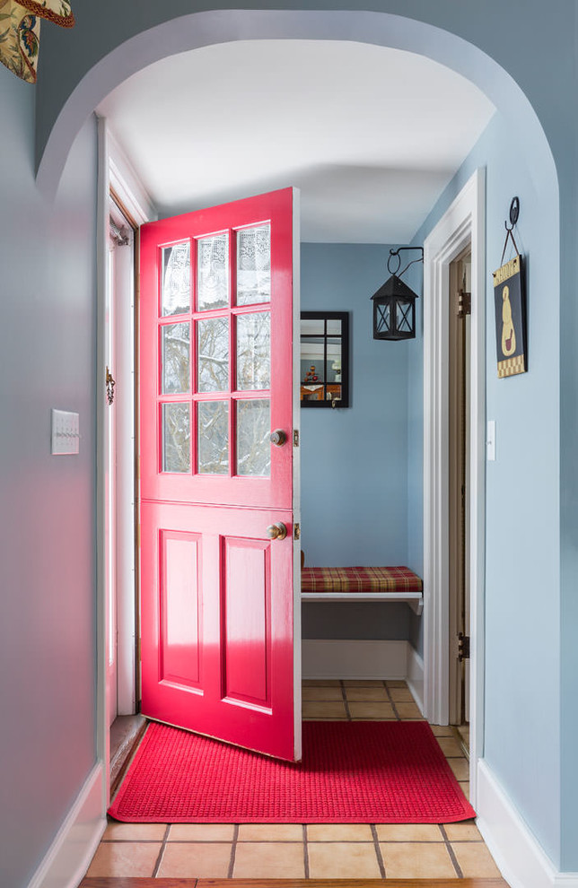 This is an example of a country entryway in New York with blue walls and a red front door.