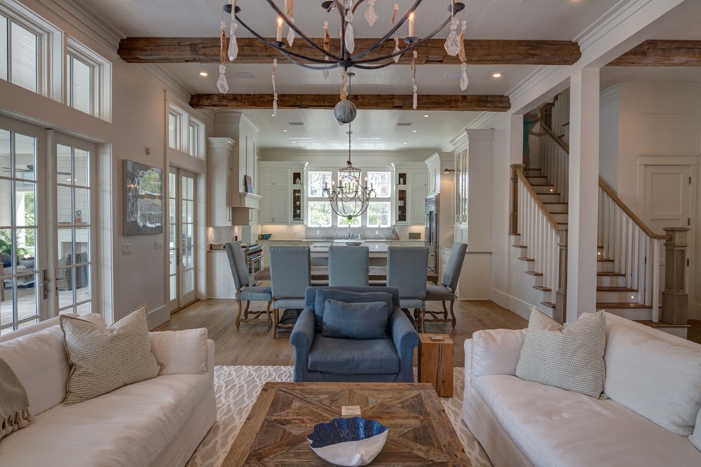 Inspiration for an expansive beach style open concept living room in Atlanta with white walls, light hardwood floors, a standard fireplace, a brick fireplace surround, a wall-mounted tv and beige floor.