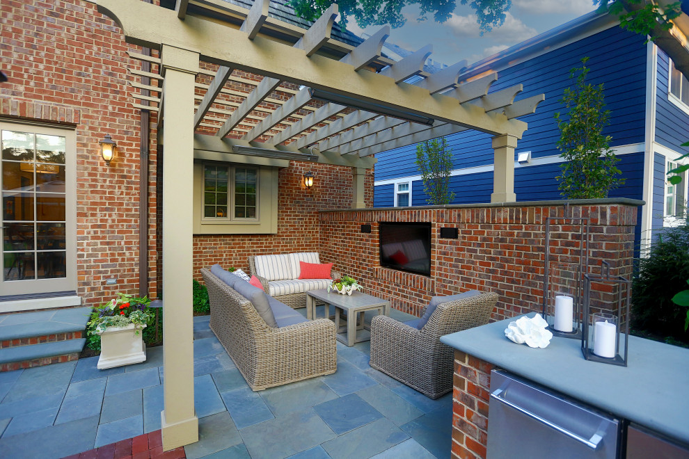 Photo of a mid-sized transitional backyard patio in Chicago with an outdoor kitchen, natural stone pavers and a pergola.