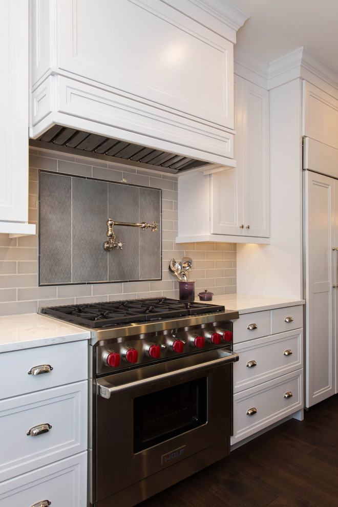 Inspiration for a mid-sized transitional u-shaped dark wood floor eat-in kitchen remodel in Boston with recessed-panel cabinets, white cabinets, quartz countertops, stainless steel appliances, an island, a farmhouse sink, beige backsplash and ceramic backsplash