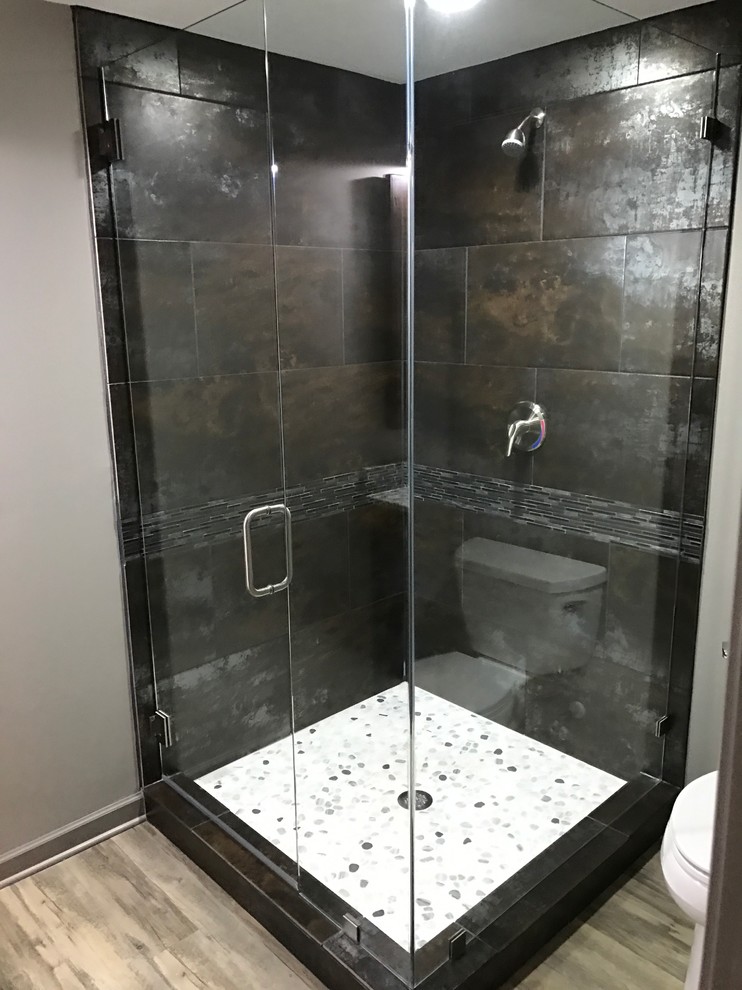 Photo of a small industrial 3/4 bathroom in Atlanta with a corner shower, a two-piece toilet, black and white tile, gray tile, multi-coloured tile, matchstick tile, grey walls and light hardwood floors.