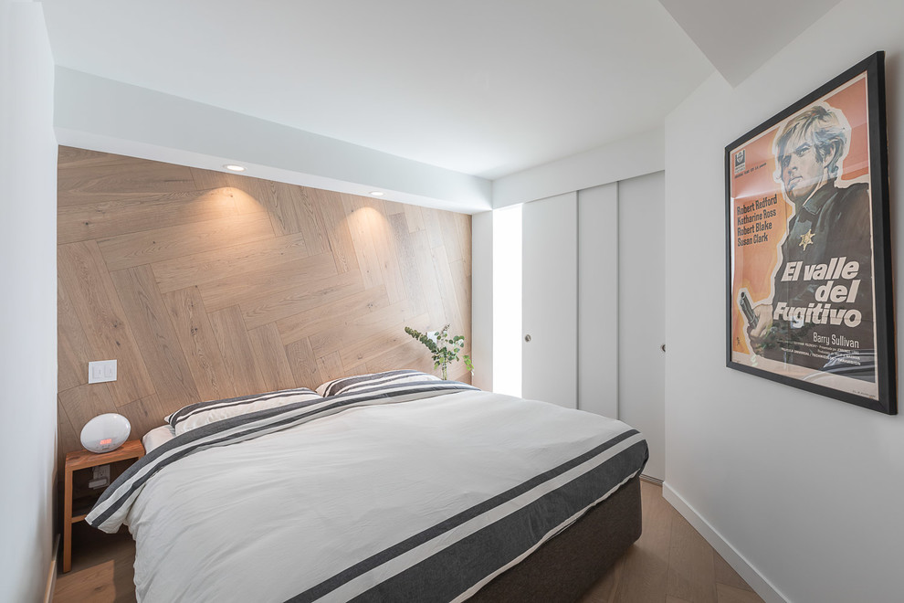 Photo of a small contemporary loft-style bedroom in Vancouver with white walls and light hardwood floors.