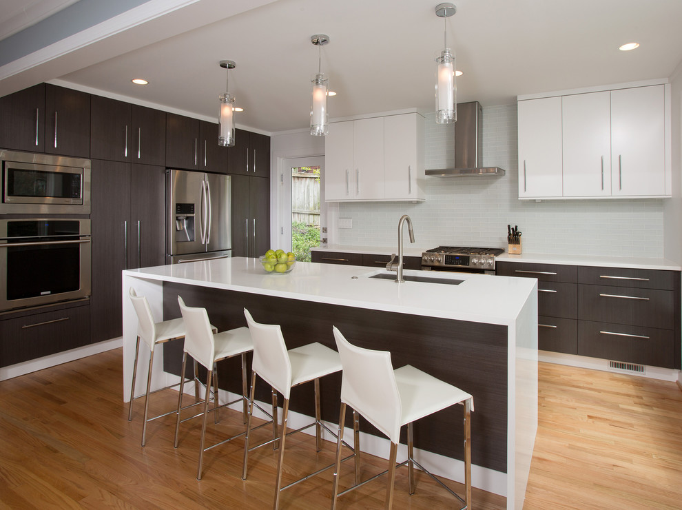 Design ideas for a mid-sized contemporary l-shaped eat-in kitchen in DC Metro with an undermount sink, flat-panel cabinets, solid surface benchtops, white splashback, stainless steel appliances, with island, dark wood cabinets, glass tile splashback and light hardwood floors.