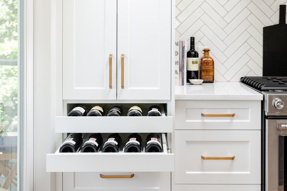 Example of a large transitional l-shaped light wood floor and beige floor open concept kitchen design in Vancouver with an undermount sink, recessed-panel cabinets, white cabinets, quartz countertops, white backsplash, ceramic backsplash, stainless steel appliances, an island and white countertops